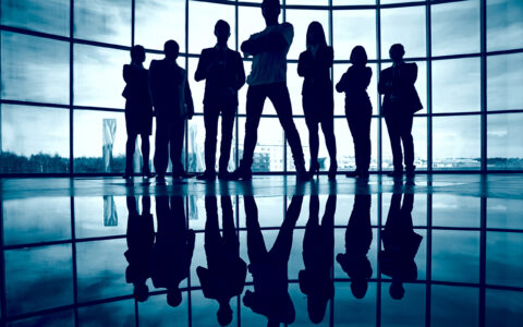 Business team standing against window with leader in front